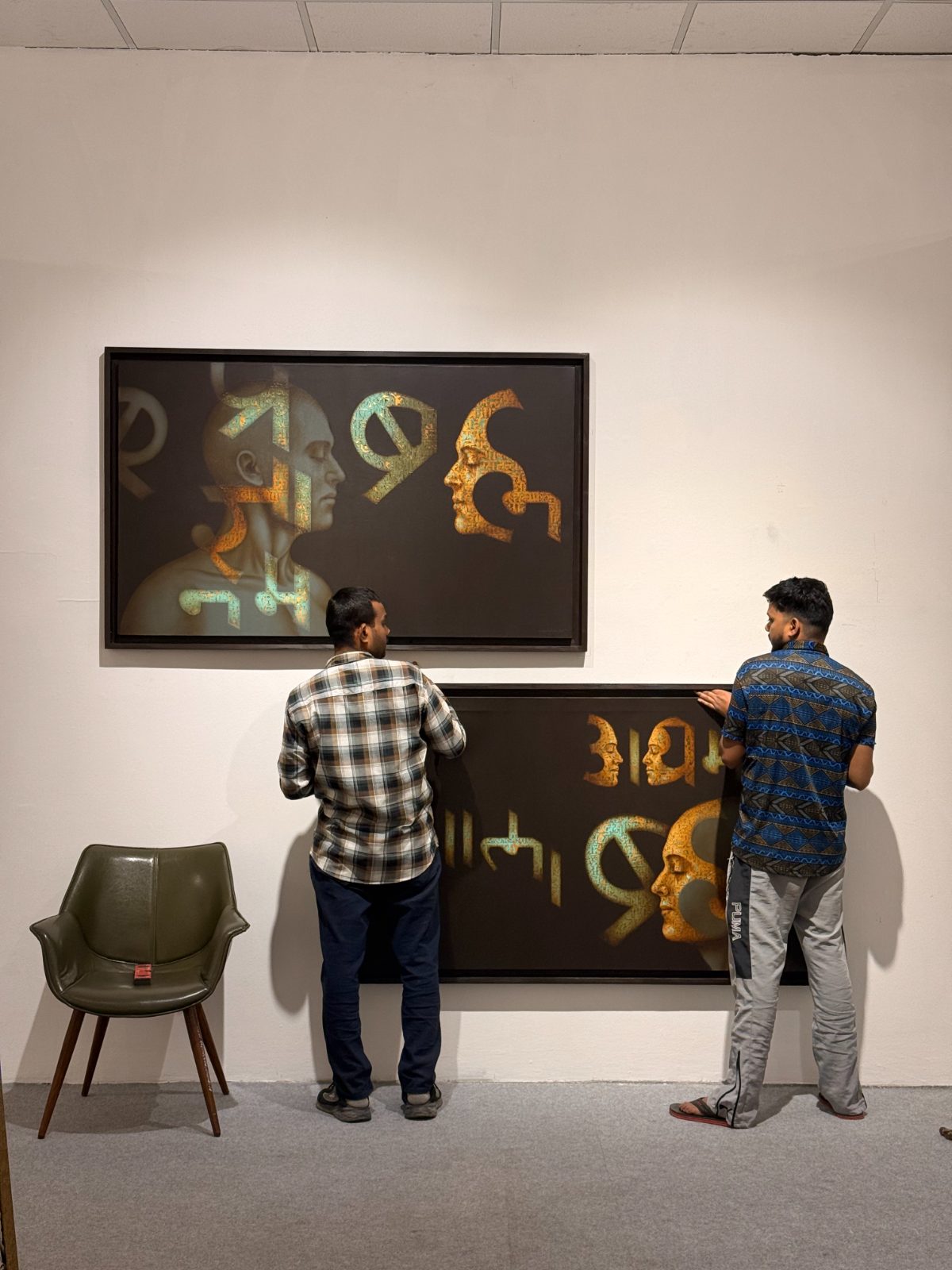 Two installers levelling the gold script paintings